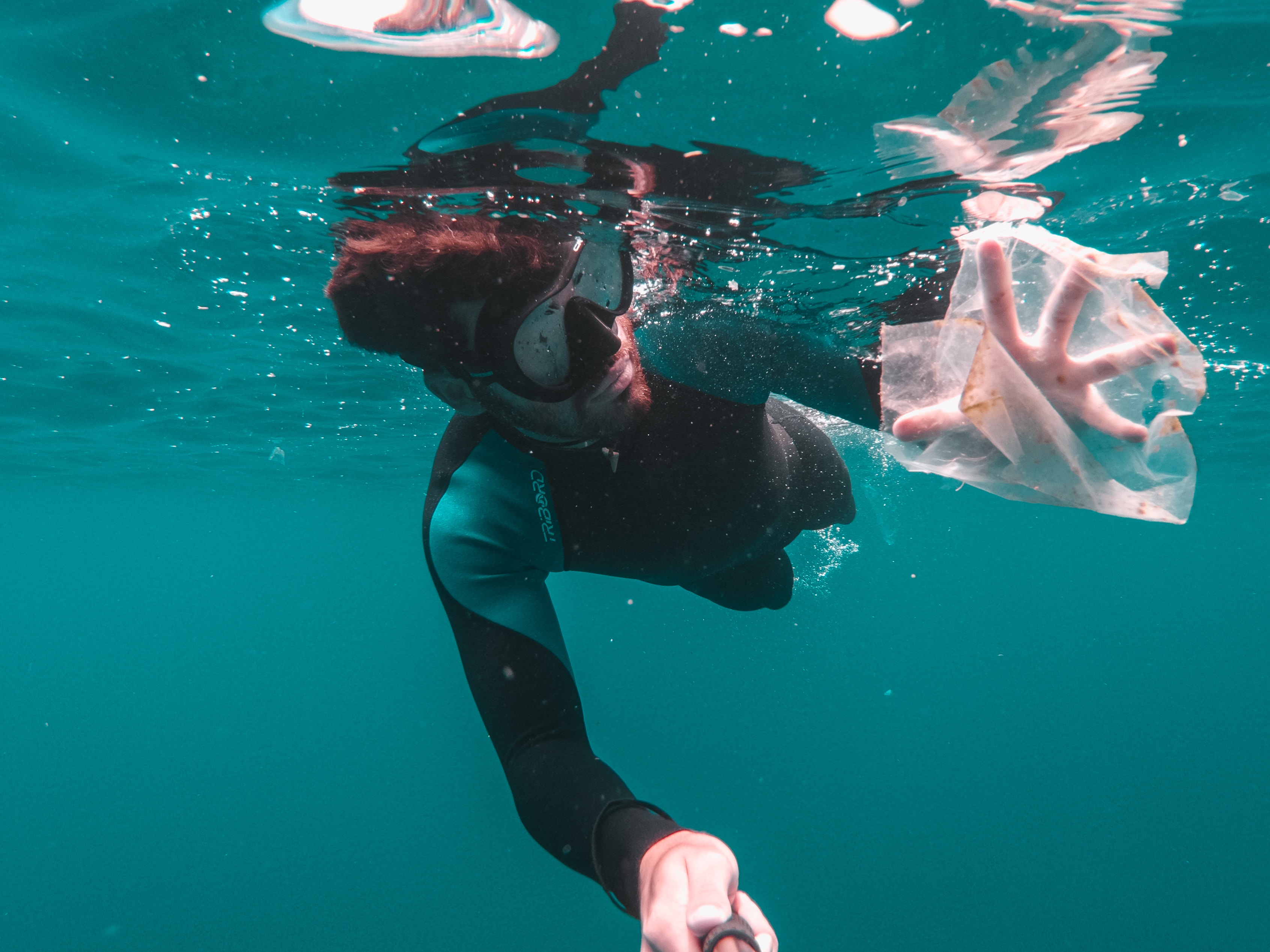 photo of man diving for trash in ocean